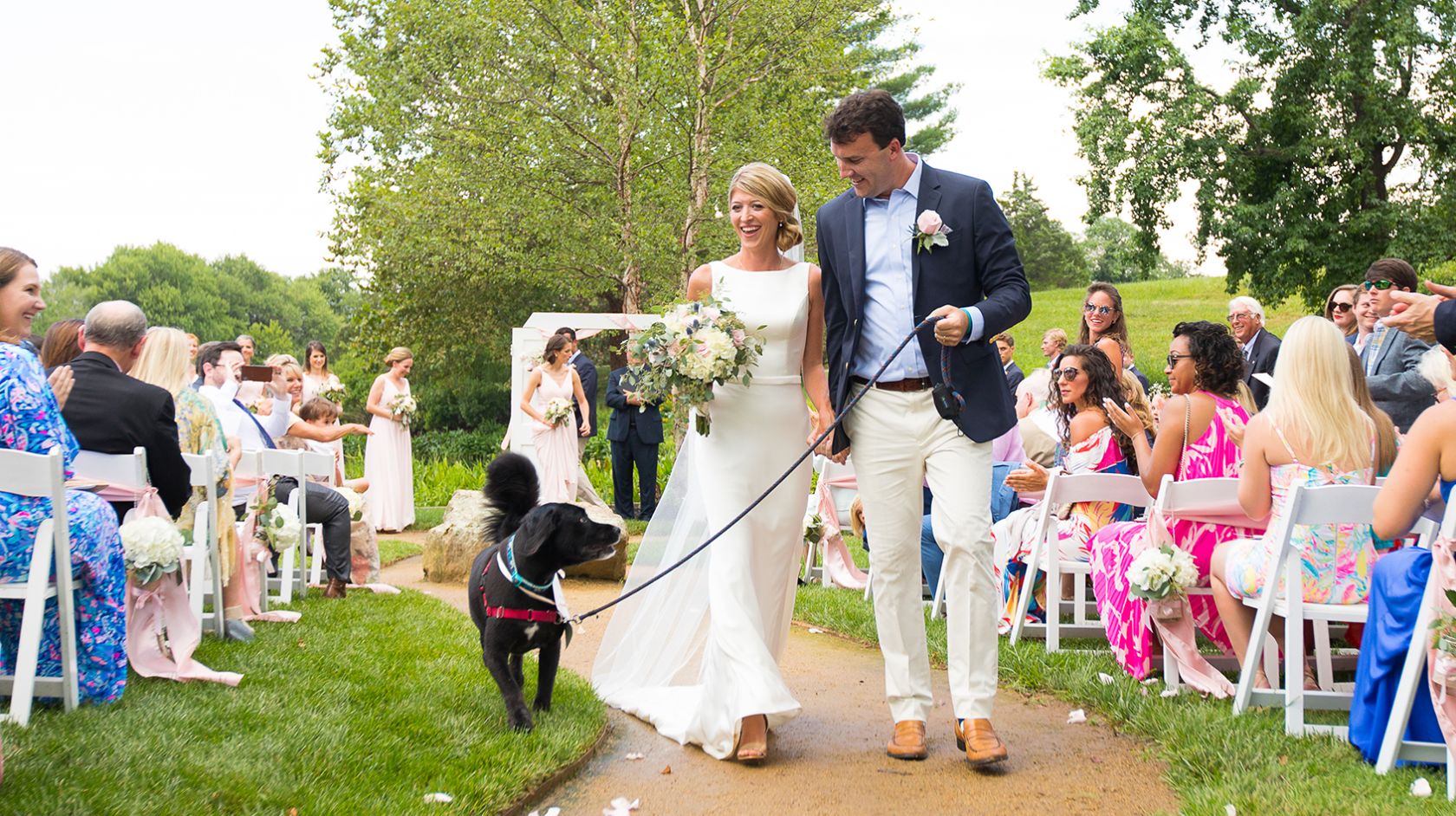 A Man And Woman Walking Down A Aisle With A Dog